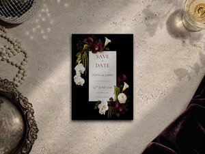 Burgundy and chartreuse floral save the date template shown on a grey surface with editorial flower artwork, pearl necklace and silver tray. Flowers include burgundy calla lilies, burgundy cymbidium orchids, white orchids, ivory roses and trailing amaranthus with chartreuse accents