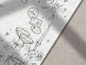 A close-up of the bottom right corner of a wedding invitation shows illustrations of champagne glasses, a candle, and passport stamps.