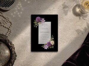Lilac floral save the date card featuring lilac allium flowers, purple delphiniums, pale lilac clematis, white orchids and Queen Anne's lace on a dark editorial background.