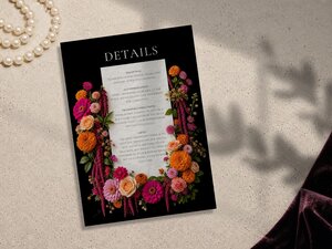 Details card for a wedding with a border of pink, orange, and red flowers on a black background.