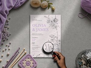 Illustrated wedding invitation featuring hidden yarn details including crochet hooks and knitting needles displayed amongst the florals, a ball of yarn beside the wedding cake, personalised champagne coupe initials and a Love Stitch menu card.