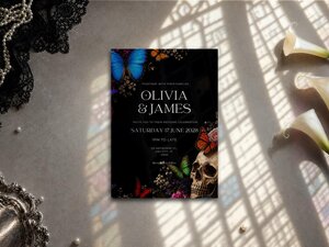 Colourful gothic wedding invitation featuring skull and butterfly artwork, vibrant jewel toned detail and dark romantic styling on a black background.
