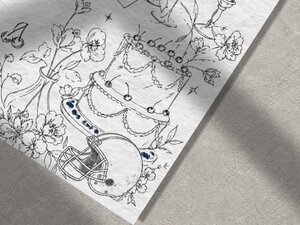 Macro view of the textured paper showing detailed line sketches of a tiered wedding cake, flowers, and an American football helmet.