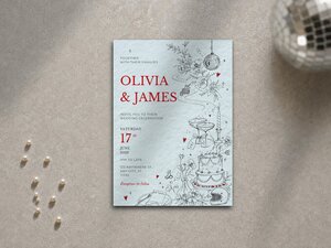 A wedding invitation card styled with a light blue textured background and black line drawings resting flat on a textured surface.