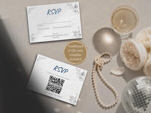 Two RSVP wedding cards displayed on a table next to a string of pearls, a glass of champagne, white flowers, and a disco ball.