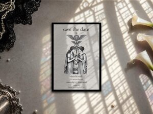 A Save the Date tarot card design lies flat on a textured surface, illuminated by geometric light shadows, with white lilies and black lace nearby.