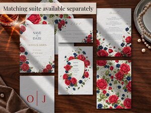 A collection of matching wedding suite cards and an envelope laid out flat on a dark wooden table, featuring red and blue floral illustrations.