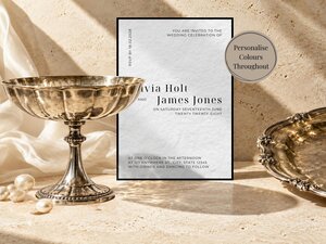 A wedding invitation card for Olivia Holt and James Jones is displayed on a textured stone surface next to a silver pedestal bowl and a silver tray.