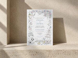 A wedding invitation rests on a beige stone ledge, featuring hand-drawn wedding and soccer doodles.