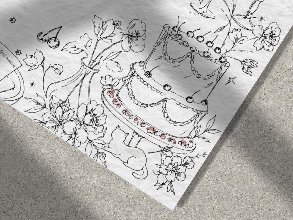 A close-up of the bottom right corner of a white wedding invitation card, showing black line art of a cake with cherries, flowers, and a cat.