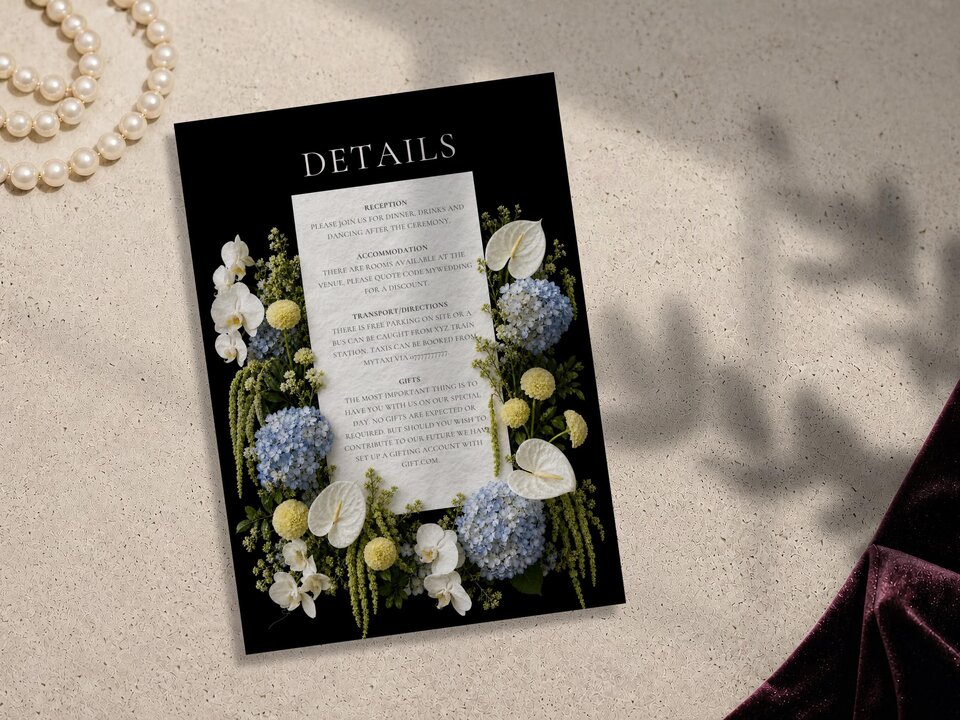 Wedding details card featuring editorial flowers on a black background, positioned on a stone surface with a pearl necklace and velvet fabric.