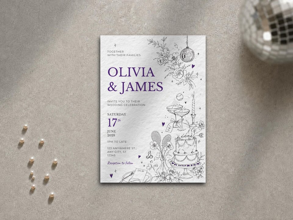 A vertical wedding invitation lies on a grey textured surface next to scattered pearls and a silver disco ball.
