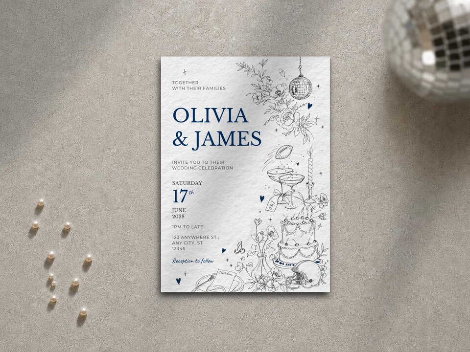 A single wedding invitation card featuring blue typography and fine-line illustrations lies on a grey surface alongside scattered pearls and a mini disco ball.
