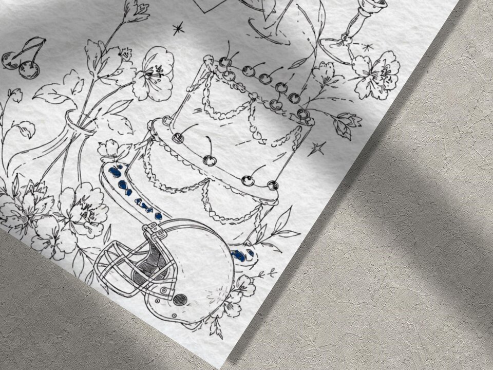 Macro view of the textured paper showing detailed line sketches of a tiered wedding cake, flowers, and an American football helmet.