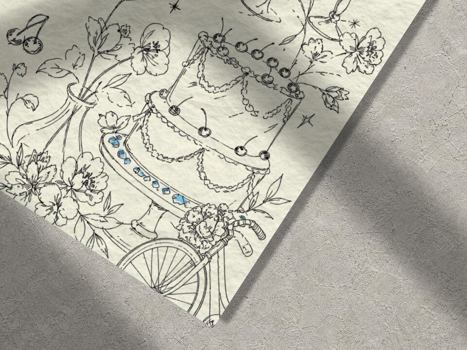 A close-up shot focuses on the lower right portion of the wedding invitation showcasing line art of a multi-tiered cake and flowers.