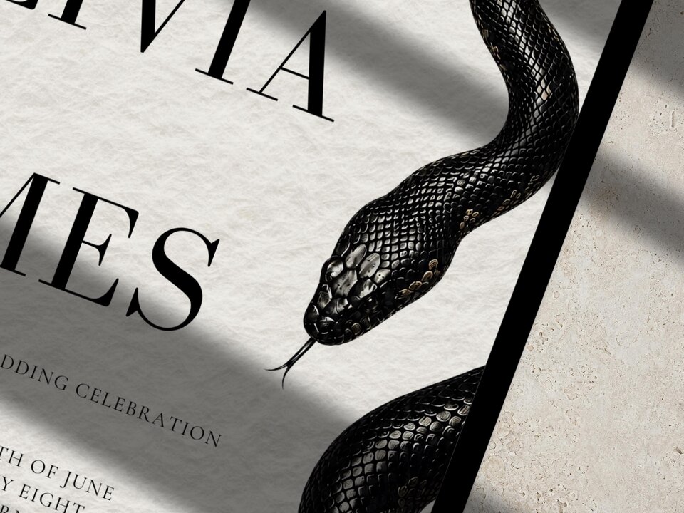 A close-up shot of the wedding invitation text and the head of the black snake illustration.