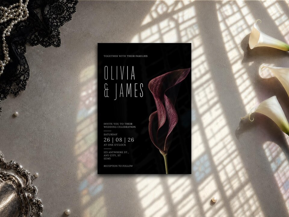 A wedding invitation rests on a textured surface featuring a dark burgundy calla lily design and white typography reading Olivia and James.