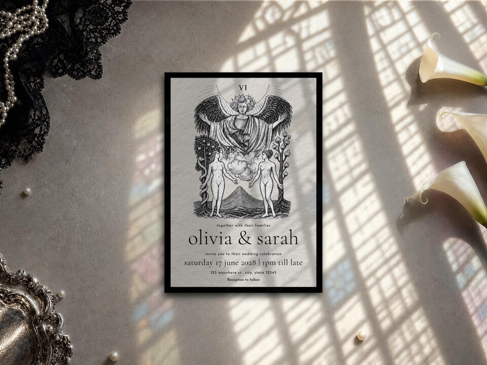The tarot wedding invitation sits on a stone textured surface near window light and white callas.