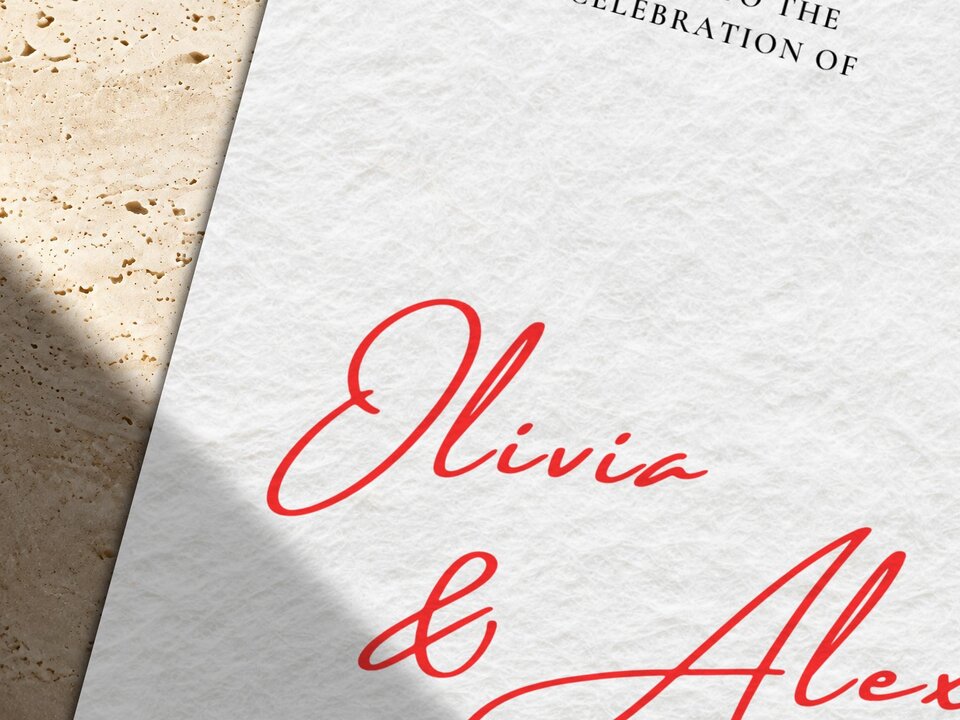Close-up detail of the red script text Olivia and Alex on a textured white wedding invitation card.