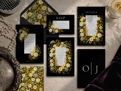 A flat lay of a wedding stationery suite featuring black cards with yellow and white floral arrangements and white text.