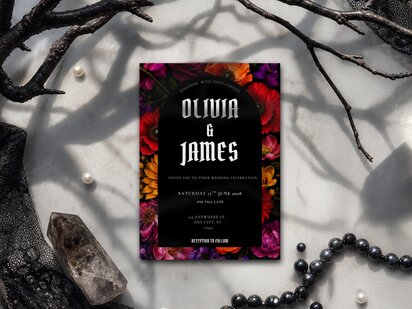 Colourful gothic wedding invitation featuring jewel tone florals on a black background with elegant typography and dark romantic styling.